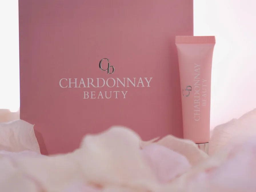 The Chardonnay Beauty box and tube standing in a drift of pink petals