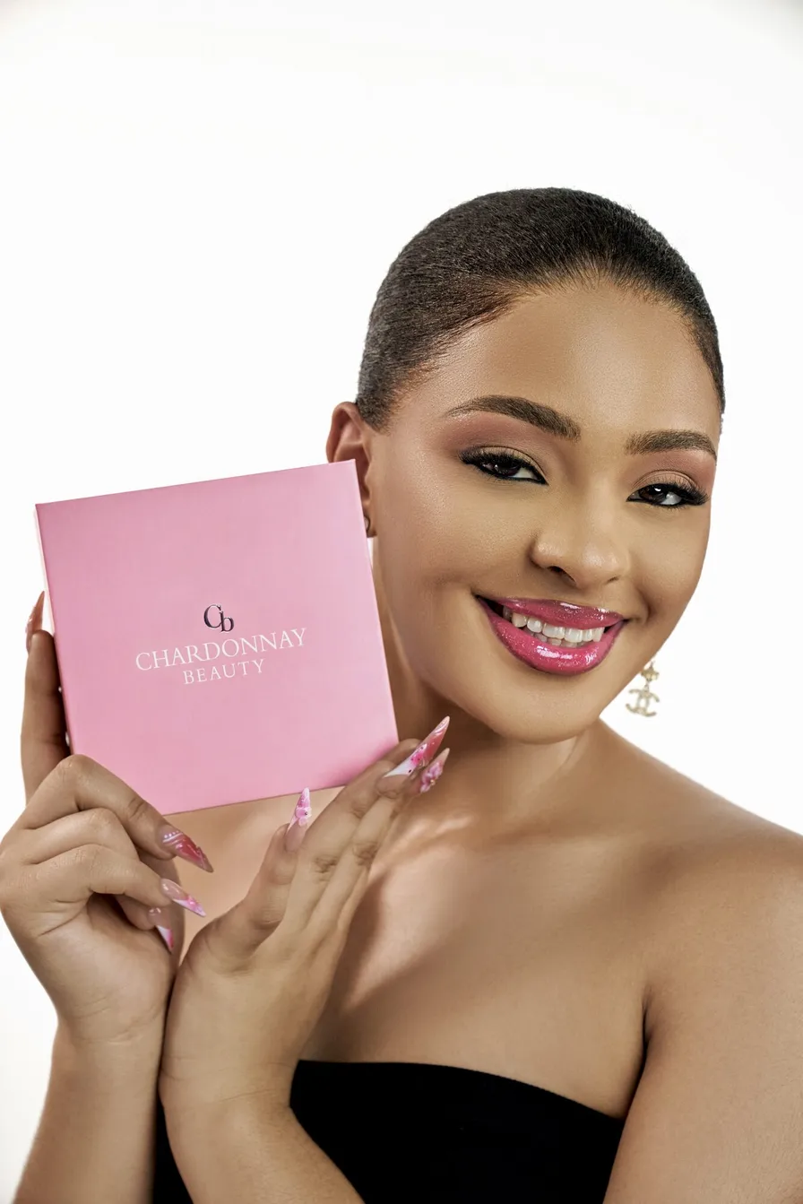 A model smiling and holding the pink Chardonnay Beauty box to her cheek